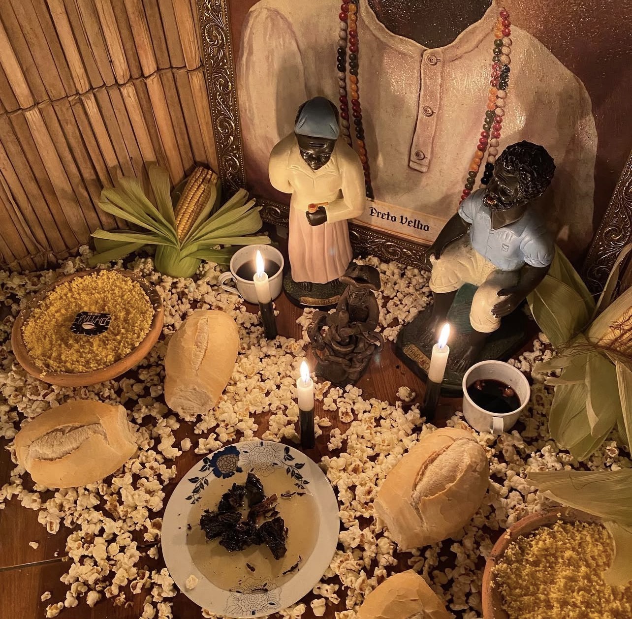 Altar de Preto Velho com velas, pipoca, pães e oferendas